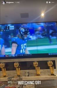 詹姆斯晒在家观看NFL比赛照片:电视下四座总冠军奖杯瞩目